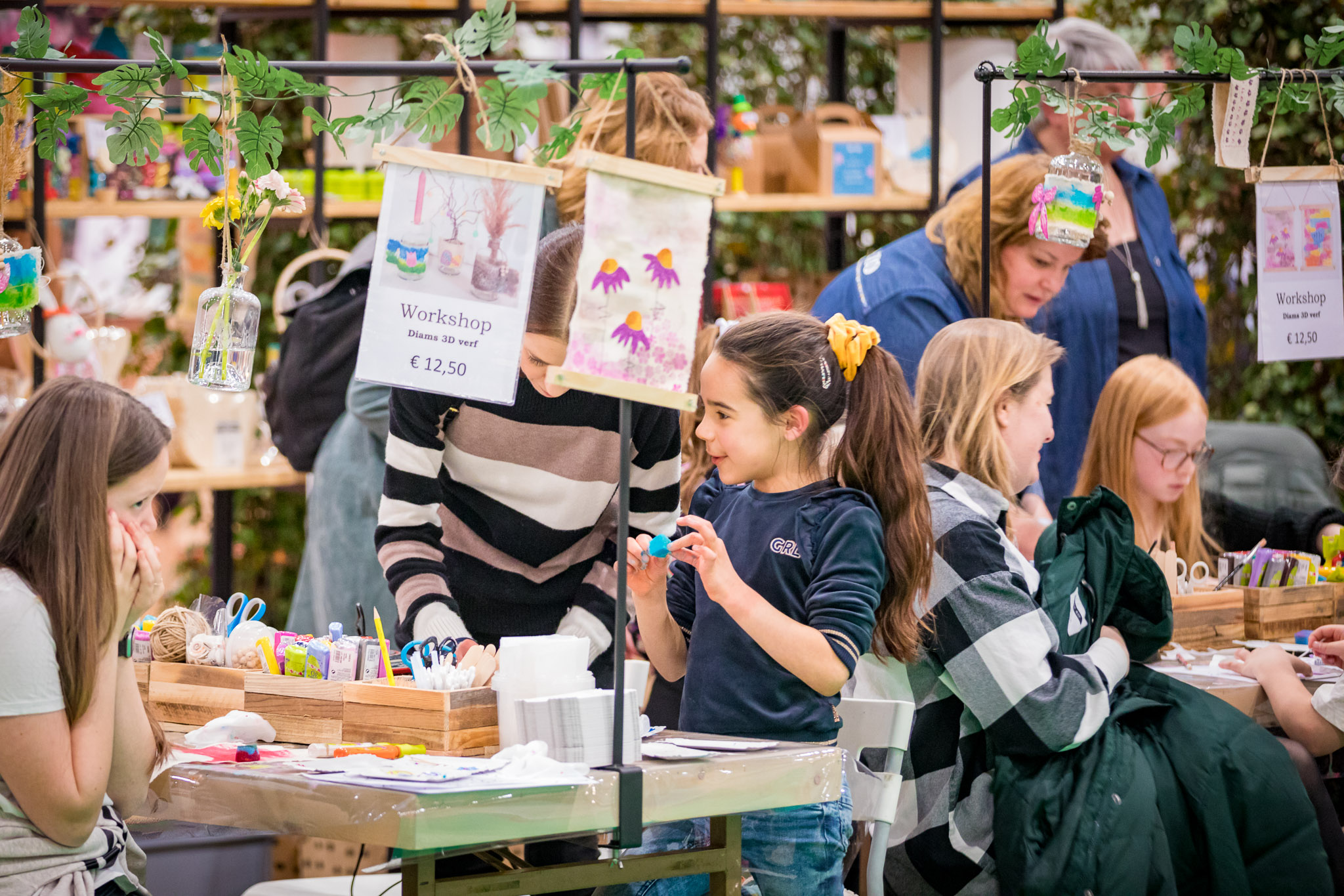 Kinderen maken creatief werk tijdens een workshop ‘Diamant 3D verf’ (€12,50) aan een knutseltafel met begeleiding.